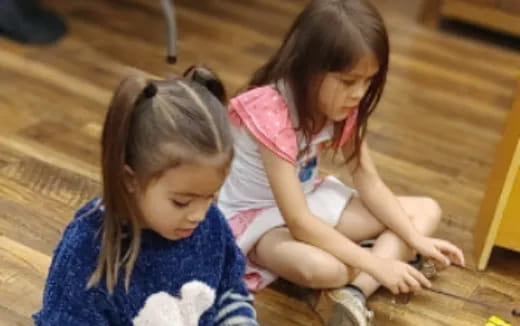 a couple of young girls playing on the floor