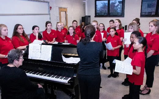 a group of people standing around a piano