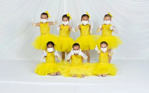 a group of children in yellow dresses