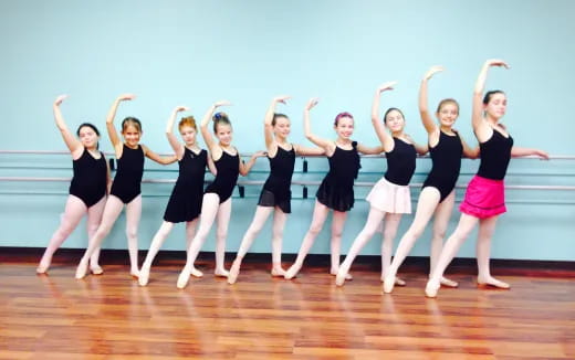 a group of women in black and white dancing on a wood floor