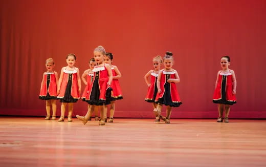 a group of children in red and black dresses on a stage