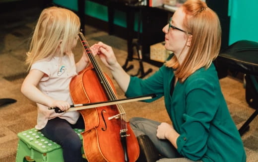 a person playing a violin with a young girl