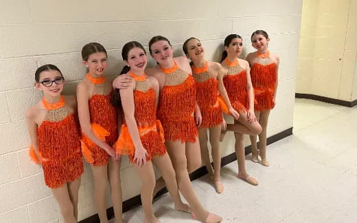 a group of girls in orange dresses