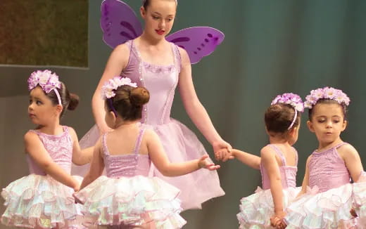a person in a dress with a group of girls in dresses