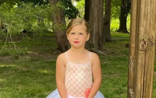 a girl in a pink dress in a forest