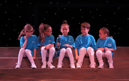 a group of children sitting on a stage