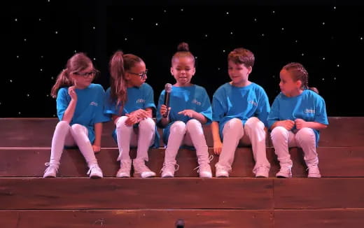 a group of children sitting on a stage