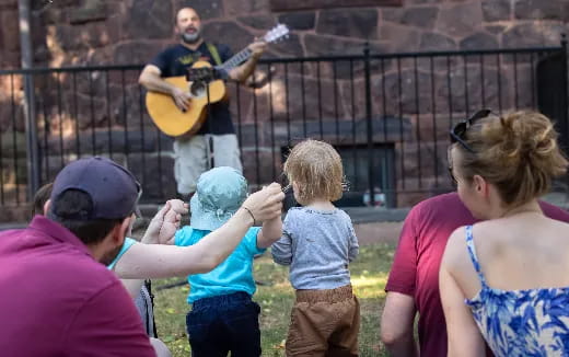 a person playing guitar in front of a group of people
