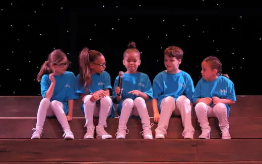 a group of children sitting on a stage