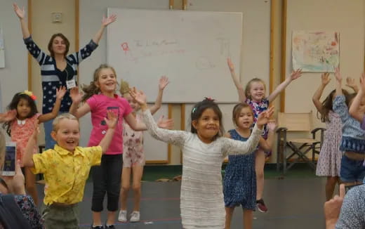 a group of children raising their hands