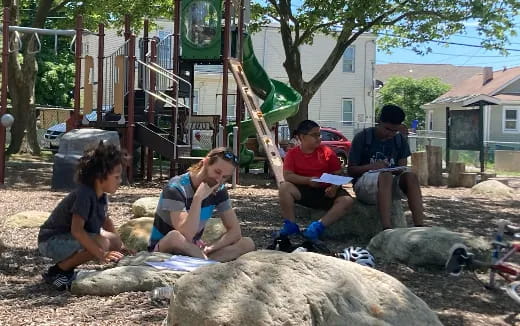 a group of people sitting on a rock in a yard
