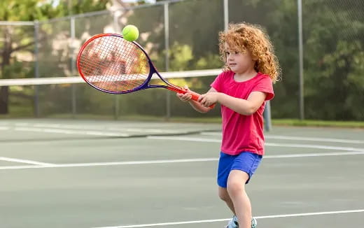 a little girl playing tennis