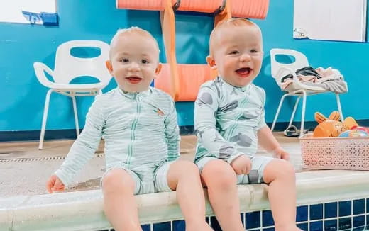 two babies sitting on a pool