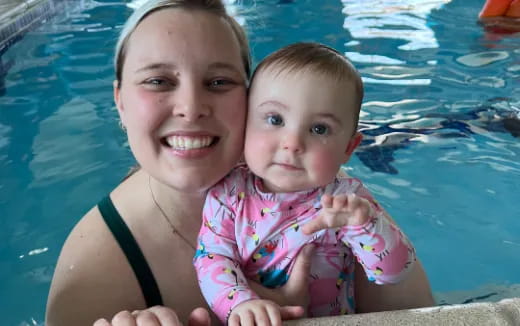 a person holding a baby in a pool