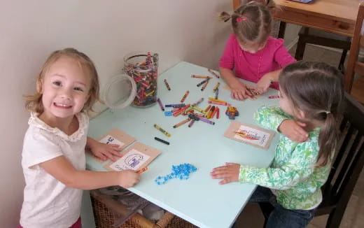 a group of children sitting at a table with art