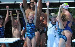 a group of people in swimsuits with their arms raised