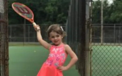 a little girl playing tennis