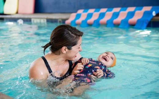 a person holding a baby in a pool