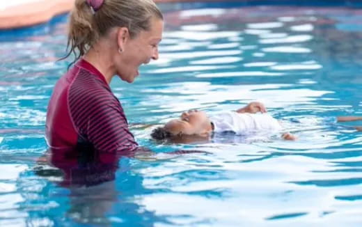 a person holding a baby in a pool