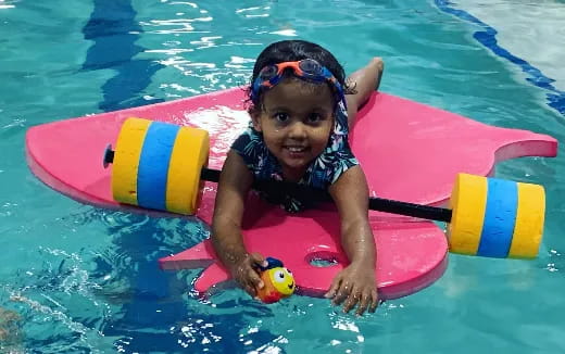 a girl in a pool with a toy in her hand