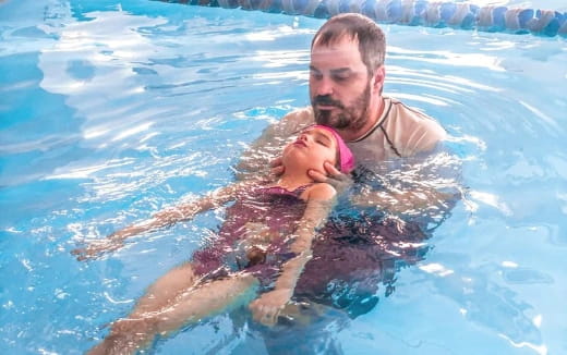 a man holding a baby in a pool