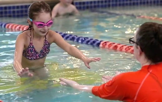 a woman in a pool with a man in the background