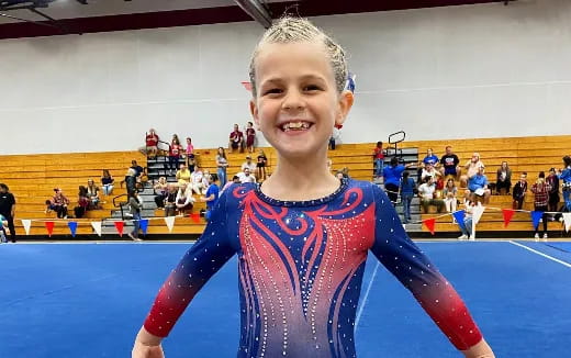 a girl in a blue leotard in a gym