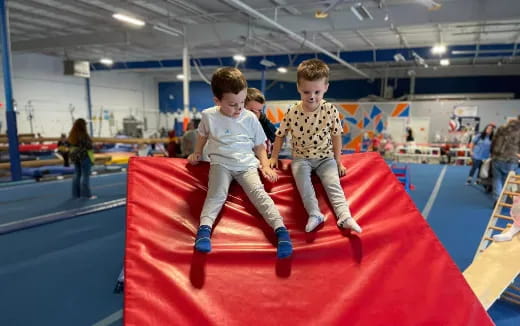 a couple of boys on a red mat in a gym