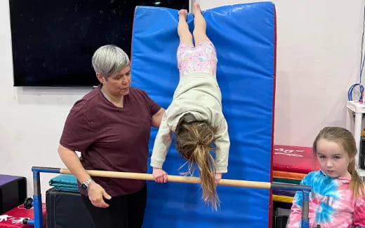 a person teaching a girl how to do a gymnastics trick