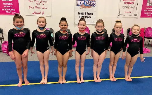 a group of girls in leotards on a mat