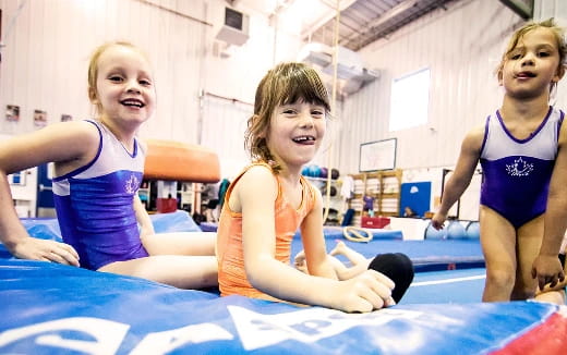 a group of girls in leotards on a mat