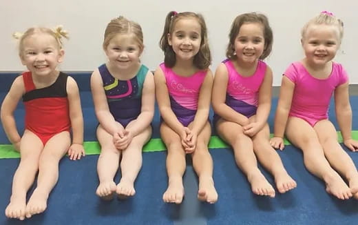 a group of girls sitting on a blue mat