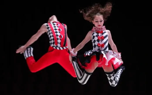 two dolls sitting on a black background