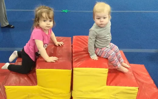 two children sitting on a yellow and red slide