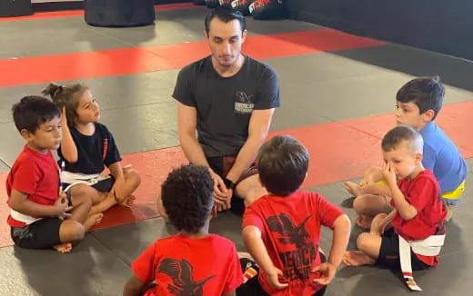 a person standing in front of a group of kids sitting on the floor