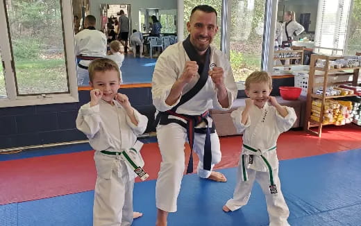 a person and two children in karate uniforms