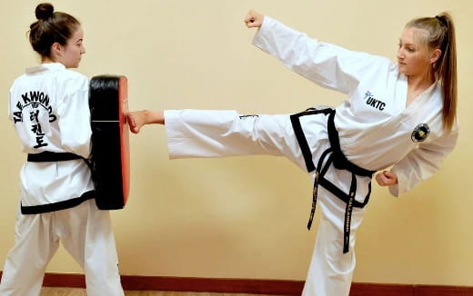a person in a karate uniform kicking another woman in the face