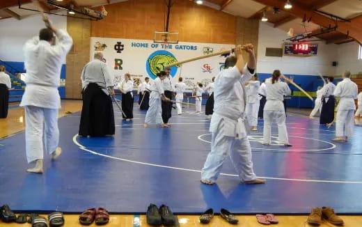 a group of people in white karate uniforms in a room with a blue floor and a white wall