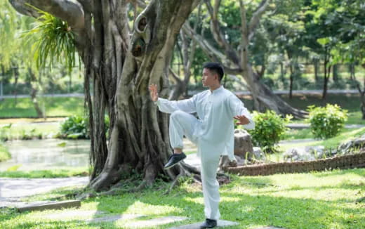 a man in a white suit standing next to a tree