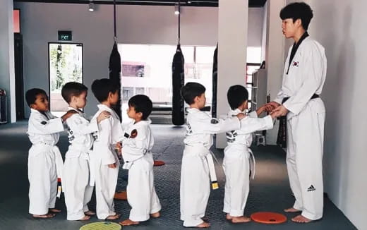 a man standing in front of a group of kids in karate uniforms