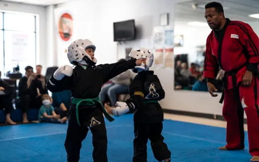 a person and two kids in a room with a crowd watching