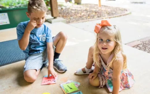 a boy and girl sitting on the ground
