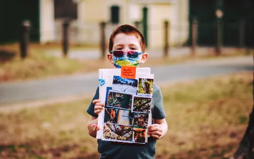 a boy with a face mask holding a book