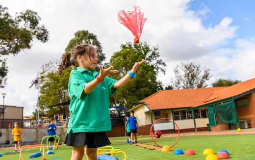 a couple of girls playing with a kite in a field