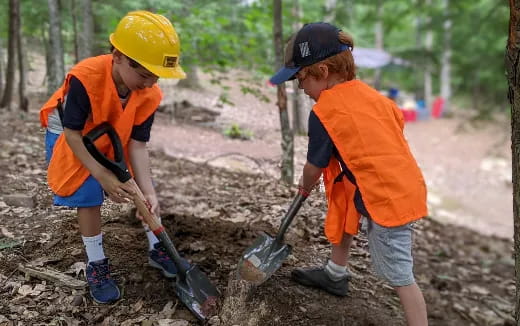 a couple of kids wearing helmets and holding a pipe