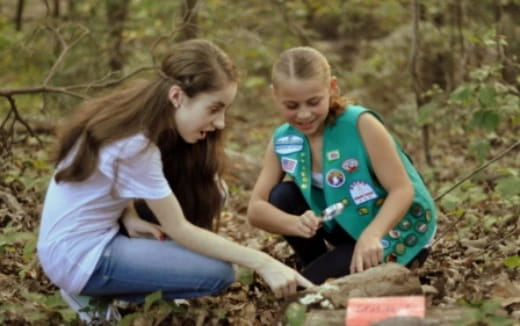 a couple of girls kneeling in the grass