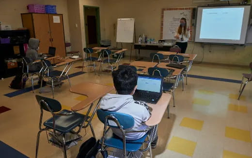 a classroom with a projector screen and students
