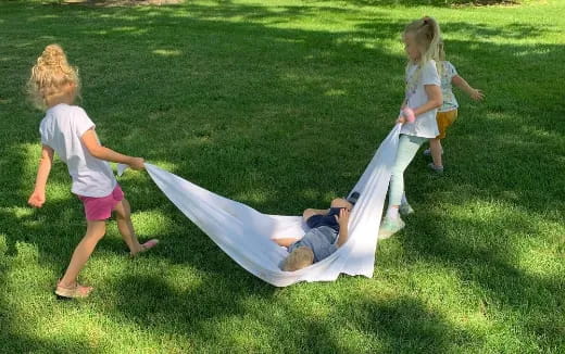 a group of children playing on a hammock in the grass