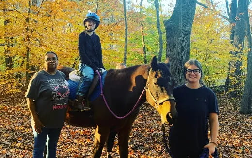 a group of people standing next to a horse in a forest