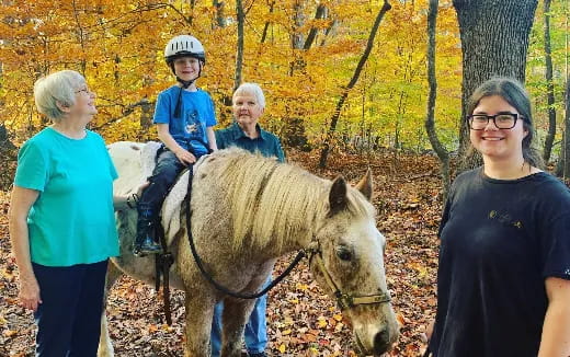 a group of people standing next to a horse in the woods